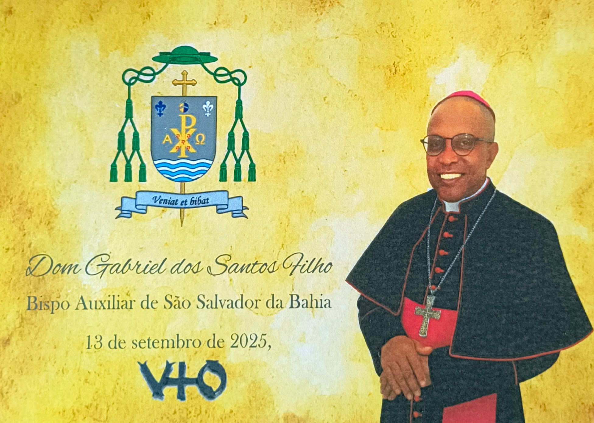 Imagem com fundo amarelo, tendo à direita um símbolo da igreja Católica; à direita uma imagem do monsenhor Gabriel